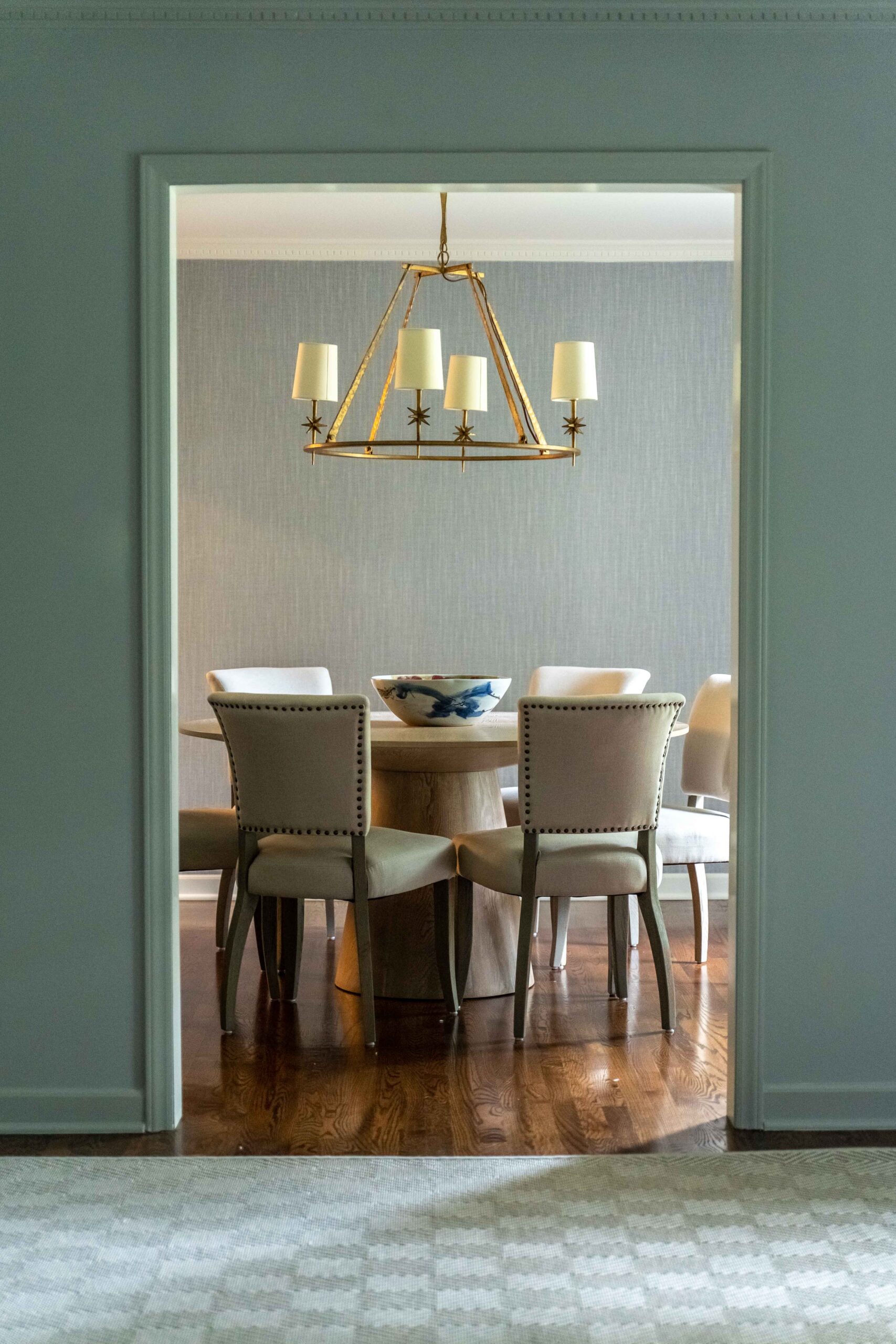 Custom dining room located in SouthPark in Charlotte, NC. The space features hardwood flooring, a round dining table, and gold chandelier.