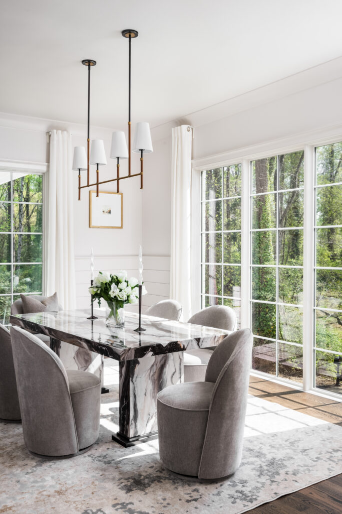 Luxury dining room with statement lighting, floor-to-ceiling windows, and abundant natural light.