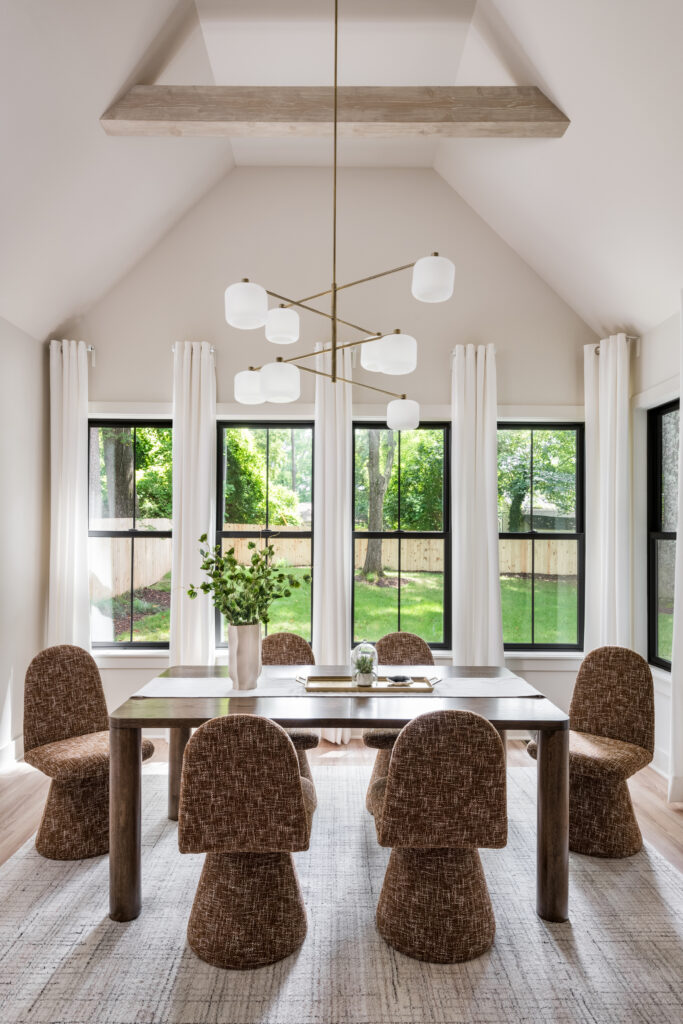 Luxury dining room with vaulted ceiling, exposed wood beams, designer lighting, and abundant natural light.
