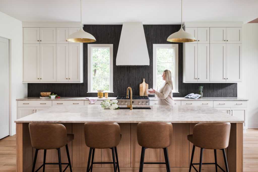 Luxury custom kitchen in Charlotte, NC with white cabinetry, wood island, natural stone countertops, and designer lighting.